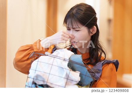 臭い洗濯物の臭いを嗅いで鼻をつまむ女性 臭い洗濯物の臭いを嗅いで鼻をつまむ女性 123409808