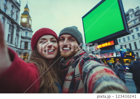 Couple taking selfie in London cityscape with green screen billboard 123410241
