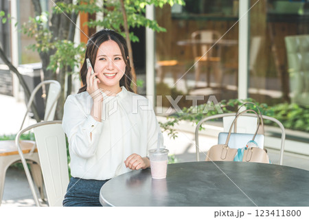 テラス席でスマホで通話する若いアジア人ビジネスウーマン 123411800