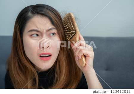 Asian woman having problem of her thick hair while using hair brush. Thick hair weights more than thin hair and prone to damage and frizzy. 123412015