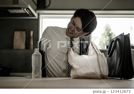 自宅でコンビニ弁当に飽きる若いアジア人ビジネスマン（栄養バランス・食生活） 123412673