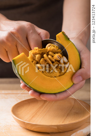 Hand holding spoon and removing seeds from pumpkin, Homemade cooking Hand holding spoon and removing seeds from pumpkin, Homemade cooking 123413724