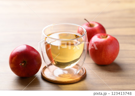 Glass of apple cider and red apple fruit on wooden background Glass of apple cider and red apple fruit on wooden background 123413748