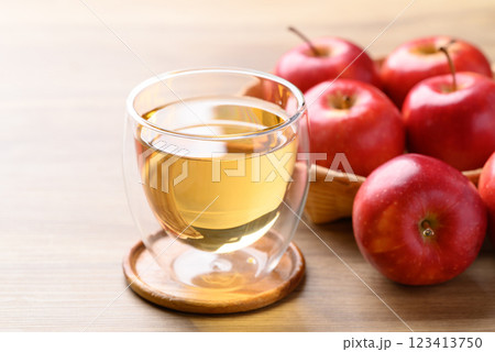 Glass of apple cider and red apple fruit on wooden background Glass of apple cider and red apple fruit on wooden background 123413750