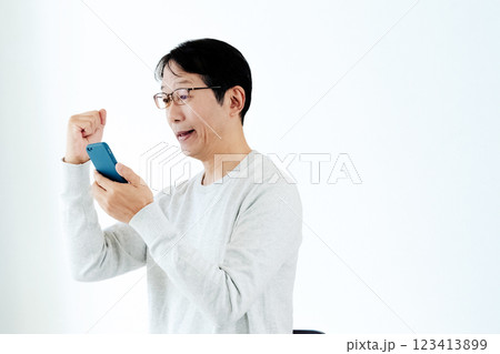 スマホを見てガッツポーズをするミドル男性 スマホを見てガッツポーズをするミドル男性 123413899
