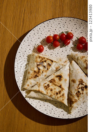 Delicious and Flavorful Flatbreads Topped with Fresh Cherry Tomatoes on a Rustic Plate Delicious and Flavorful Flatbreads Topped with Fresh Cherry Tomatoes on a Rustic Plate 123413980