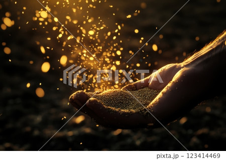 A hand holding a handful of sand with a bright light shining on it 123414469