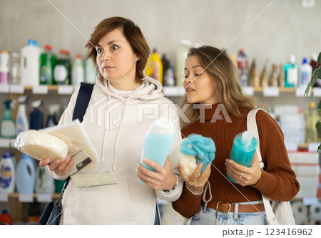 Mum with adult daughter purchases household chemicals in store, choose shower gel and body washcloth 123416962