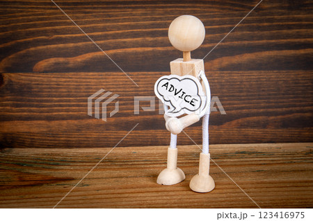 Advice. Miniature man with speech bubble in hands on wood texture background Advice. Miniature man with speech bubble in hands on wood texture background 123416975