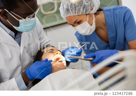 Orthodontist and chairside assistant working on dental restoration for woman 123417286