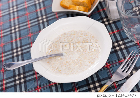 There is portion of freshly prepared milk oatmeal porridge in plate 123417477