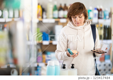 Store visitor woman purchases in household chemicals department, choose eye shadow pallet Store visitor woman purchases in household chemicals department, choose eye shadow pallet 123417484