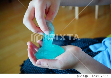 小学生の子供がスライムを手で伸ばして遊んでいる様子。 123417887