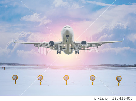 White passenger aircraft take off from winter airport runway against the backdrop of a scenic evening sky with sun rays White passenger aircraft take off from winter airport runway against the backdrop of a scenic evening sky with sun rays 123419400