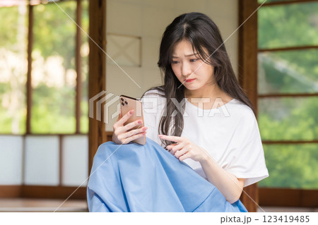 古民家の縁側で悩みながらスマホをタップする若い女性 古民家の縁側で悩みながらスマホをタップする若い女性 123419485