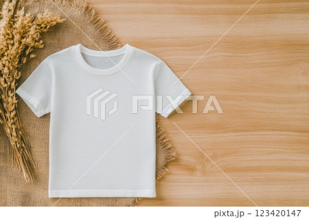 Minimalist photo of a blank white t-shirt on a wooden table with dried wheat branches 123420147
