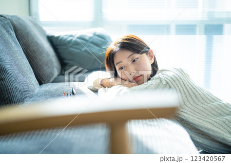 窓辺のソファで物思いにふける女性 窓辺のソファで物思いにふける女性 123420567