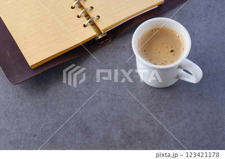 ミルクをたっぷり入れたコーヒー、カフェ・ラッテを飲みながら、システム手帳でデスクワーク中のイメージ 123421178