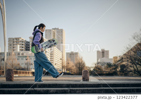 スケートボードを抱えて公園を歩く女性 123422377