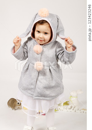 Playful Toddler in Bunny Costume Standing with Raised Hands and Easter Decorations 123423246
