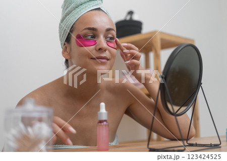 Natural beauty: A woman applies under-eye patches, engaging in anti-aging procedures to combat wrinkles and rejuvenate her beauty. Natural beauty: A woman applies under-eye patches, engaging in anti-aging procedures to combat wrinkles and rejuvenate her beauty. 123424525