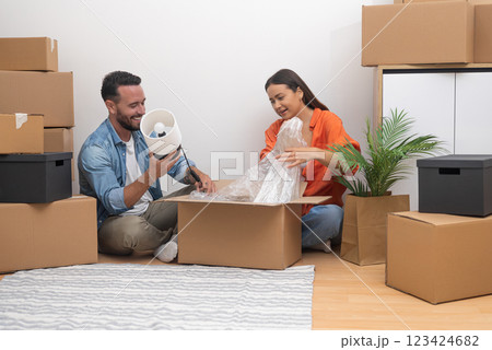Married couple enjoys moving in new contemporary flat in another city together checking various carton boxes with stuff for interior decoration 123424682