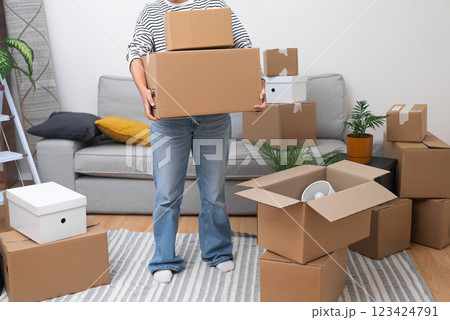 Female carries cardboard boxes taken to new address for unpacking in living room of new residential building rearranging things and moving to modern flat 123424791