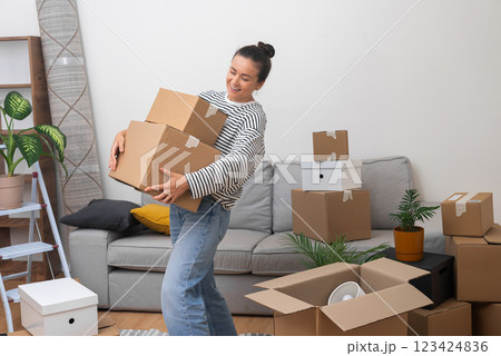 delighted woman moves to her new home, standing in the living room with a pile of cardboard boxes, experiencing the joy of her arrival 123424836