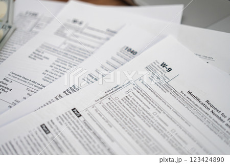 Request for Taxpayer Identification Number and Certification form placed on set of tax forms necessary for taxpayers to ensure accurate reporting of income 123424890