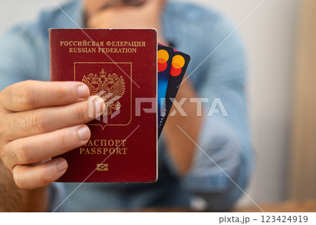 Male entrepreneur shows Russian Federation passport with credit cards hinting about challenges of international financial transactions for local businesses Male entrepreneur shows Russian Federation passport with credit cards hinting about challenges of international financial transactions for local businesses 123424919