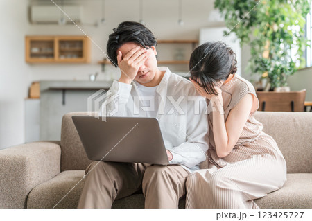 パソコンを見ながらショックを受ける夫婦・カップル（詐欺・投資・失敗・騙される） 123425727