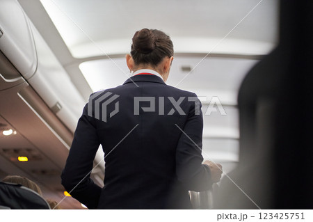 An unrecognizable flight attendant serves hot drinks on board the plane. View of the ceiling in the hallway of the plane. High quality photo 123425751
