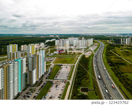 An Aerial View Showcasing Modern Urban Development Located Adjacent to a Busy Highway 123425762