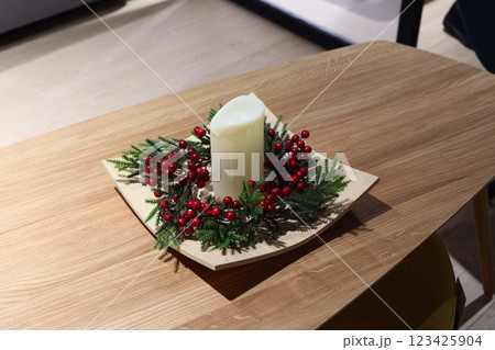 An Elegant Candle Centerpiece adorned with vibrant Red Berries and lush Greenery elements 123425904