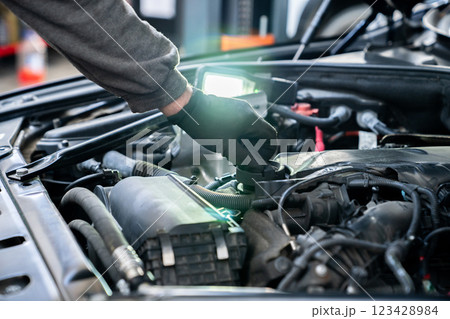 Serviceman checks the oil level in a car engine 123428984