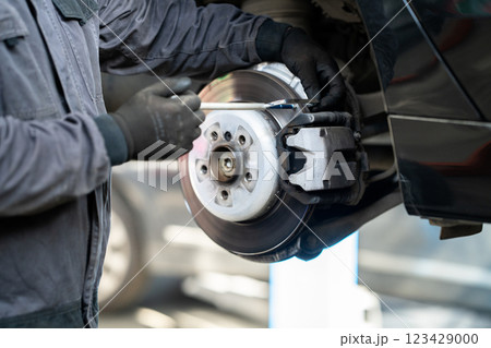 Serviceman checks the brake discs of a car 123429000