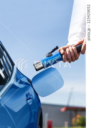 Man holds a hydrogen fueling nozzle on a hydrogen filling station. Refueling car with hydrogen fuel Man holds a hydrogen fueling nozzle on a hydrogen filling station. Refueling car with hydrogen fuel 123429052