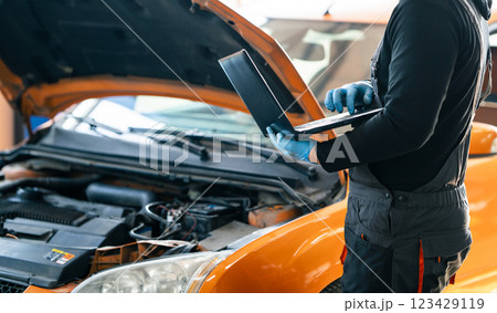Serviceman with laptop checks car software in car service 123429119