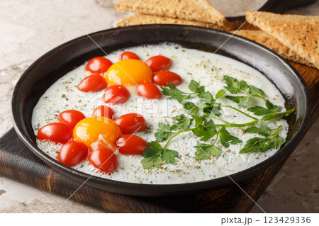 Flower shaped breakfast idea cooked fried eggs, parsley and cherry tomatoes close-up in a plate. Horizontal 123429336