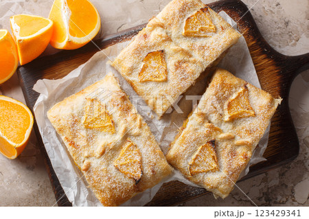 Homemade orange puff pastry pie with walnuts, raisins and fresh fruits close-up on wooden board. Horizontal top view 123429341