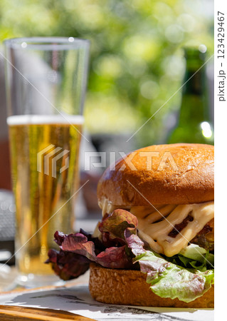 delicious gourmet burger made with a juicy patty, topped with melted cheese, fresh lettuce and generous amount sauce creating a perfect balance of flavors. Glass of beer. enjoyable dining atmosphere delicious gourmet burger made with a juicy patty, topped with melted cheese, fresh lettuce and generous amount sauce creating a perfect balance of flavors. Glass of beer. enjoyable dining atmosphere 123429467