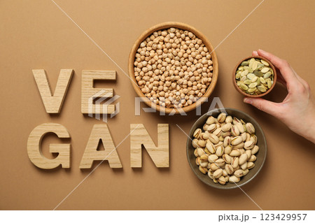 Nuts and seeds in bowls, hand and wooden letters on beige background, top view 123429957