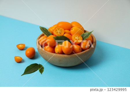 Kumquat in wooden bowl on blue table on white background Kumquat in wooden bowl on blue table on white background 123429995