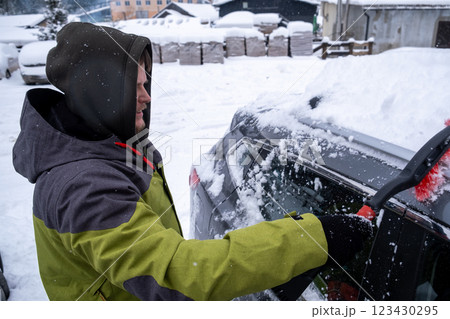 Person Clearing Snow from Car in Winter Landscape 123430295