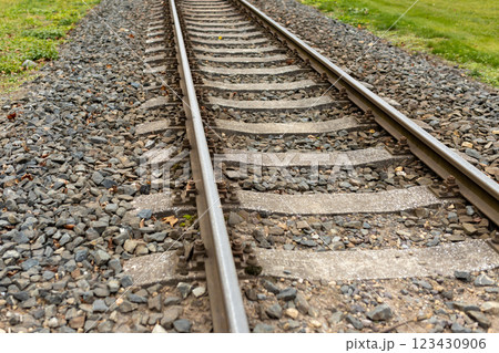 Single, diagonal railroad track through countryside landscape with a grass field. Empty railway track. Travel, adventure concept Single, diagonal railroad track through countryside landscape with a grass field. Empty railway track. Travel, adventure concept 123430906