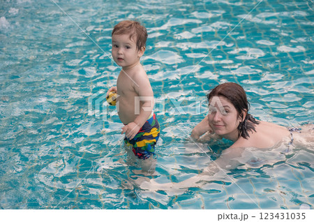 A Caucasian woman and her one-year-old son swim in a pool. A Caucasian woman and her one-year-old son swim in a pool. 123431035