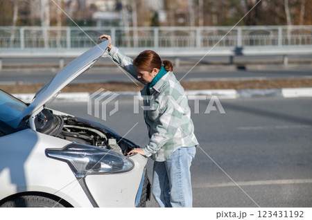 Caucasian woman looks puzzled under the hood of a car. Caucasian woman looks puzzled under the hood of a car. 123431192