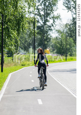 Rear view of Caucasian woman riding bike in park. Vertical photo. Rear view of Caucasian woman riding bike in park. Vertical photo. 123431295