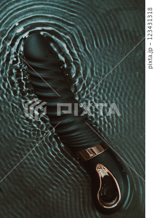 Black silicone vibrator in water. Circles on water around sex toy. Black silicone vibrator in water. Circles on water around sex toy. 123431318