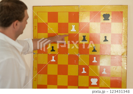 Caucasian man standing at wall mounted magnetic chessboard demonstration. Caucasian man standing at wall mounted magnetic chessboard demonstration. 123431348